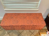 Closed storage bench showing damask upholstery