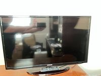 Front view of Samsung 32 inch LED TV on stand with remote placed in front