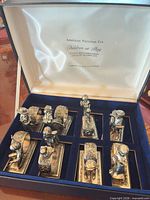 Eight figural napkin rings in blue velvet presentation box, satin lid with collection title