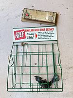 Full view of green wire rack with tin sign and postcard bundle