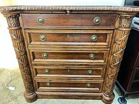 Front view showing five drawers, carved columns, brass hardware