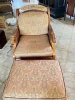 Front view of armchair and ottoman showing overall style, upholstery pattern and leather trim