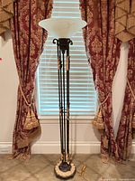 Full view of black and gold torchiere lamp in front of window