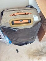 Top view of beige woven suitcase showing telescopic handle, carry handle and zipper