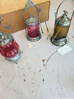 Three pickle castors showing glass colors, frames, lids and tongs