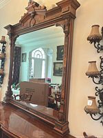 Framed decorative mirror atop buffet showing carved crest and column details