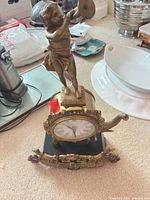 Full front view of brass Rococo mantel clock on black base