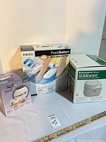 Three boxed items: HoMedics Foot Spa, Kenmore Humidifier, Body Basics Diffuser