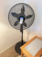 Full view of black Lasko pedestal fan on stand