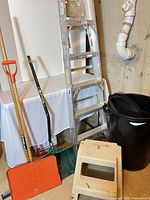 Group shot of all five items: ladder, two shovels, trash can, stool