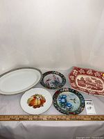 Group shot of all five items including oval platter, two round hummingbird plates, fruit plate, red rectangular plate