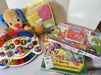 Group shot of entire lot including plush puppy, piano, fabric blocks, board games, construction paper, rings