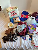 Assorted dog supplies including training pads, diapers, bowl, clothing, e-collar, gloves box, puzzle toy