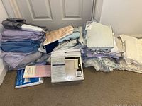 Overall lot showing stacked folded linens and packaged sheet set
