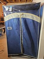 Full view of portable wardrobe with navy cover, beige trim, clear vinyl front