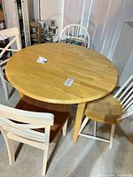 Round wood dining table with 3 of 4 chairs visible