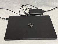 Closed Dell Latitude laptop with AC adapter connected