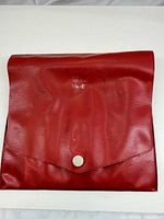 Closed red vinyl pouch with snap closure