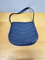 Front view of navy crossbody purse showing chevron stitching and shape