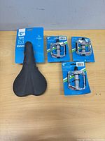 Package front of 49N Perch 153 women’s saddle and three packages of 49N pedals on table