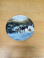 Front view of round collector plate showing winter scene artwork