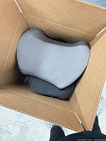 Open box showing grey cushion on top of other cushions