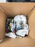 Top view of box showing mixed loose and bagged throw blankets