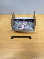 Closed box opened showing individually bagged pulls and screws