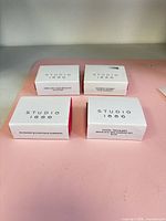Four Studio 1886 jewelry boxes on a pink surface