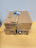 Three cardboard boxes stacked, one nozzle visible in opening