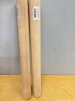 Two wooden dowel rolling pins standing vertically showing full length