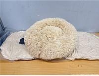 Shaggy beige donut bed on top of two vacuum-packed beds