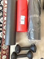Two foam rollers (one black wrapped, one red) and pair of dumbbells