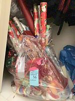 Bagged lot showing multiple Christmas wrapping paper rolls, ribbons and bows