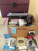 Box showing various office supplies including Lenmar adapter, tape, Sharpie pack