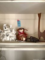 Shelf view showing ghost lantern, plush dog, abstract cat figure and two metal stands
