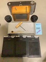 Group shot of all items including film holders, camera back, developing parts, plate and screwdriver