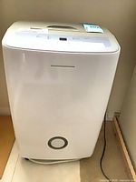 Front view of white Frigidaire dehumidifier showing circular water-level indicator and power cord
