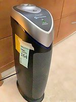 Front view of GermGuardian tower air purifier showing control dial, grills, and attached power cord