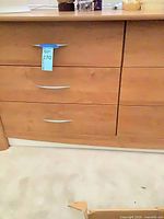 Front view of light brown six-drawer dresser showing handles, finish and wear