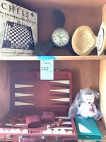 Shelf showing Chess4 box, propeller clock, Flintstones pottery, backgammon set, Maple plush
