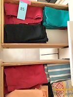 Shelved stacks showing red, black, teal, peach, striped and printed fabrics