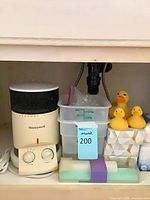 Overall lot showing heater, containers, rubber ducks on tissue box, squeegee package