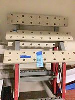 Overall view of both foldable sawhorses showing bench tops with dog holes and red legs