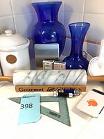 Group shot showing marble rolling pin, blue vases, ceramic jar, digital scale, playing cards, measuring cups/spoons and small accessories