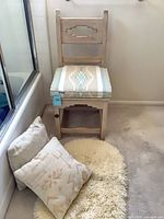 Front angled view of wooden chair with Southwestern cushion, two pillows and shag rug in foreground