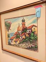 Full view of framed village and seascape painting