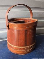 Full view of cylindrical wooden sewing basket with handle