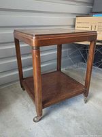 Full view of solid wood side table showing top, legs, shelf, casters