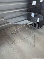 Full view of accent table showing round glass top and chrome wire base